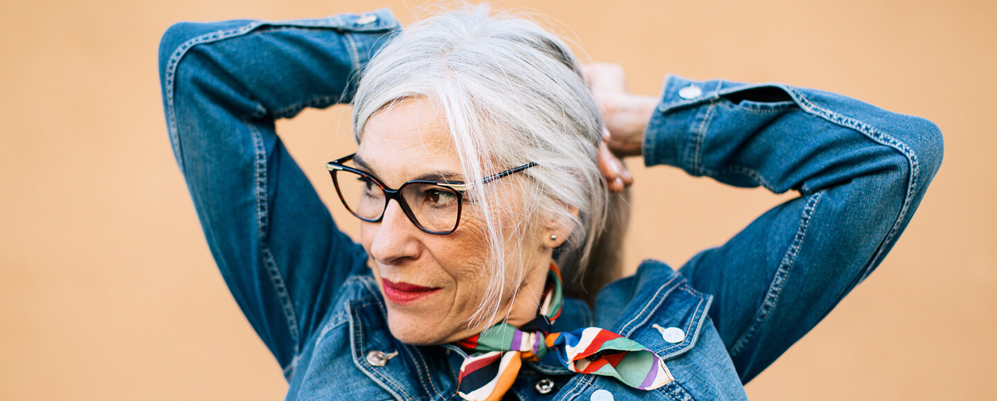 Confident midlife woman tying her hair back, embracing a timeless outlook and an ageless attitude