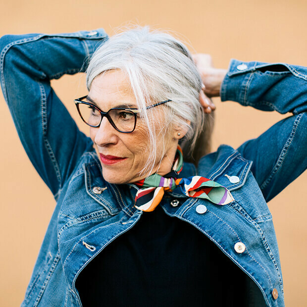 Confident midlife woman tying her hair back, embracing a timeless outlook and an ageless attitude